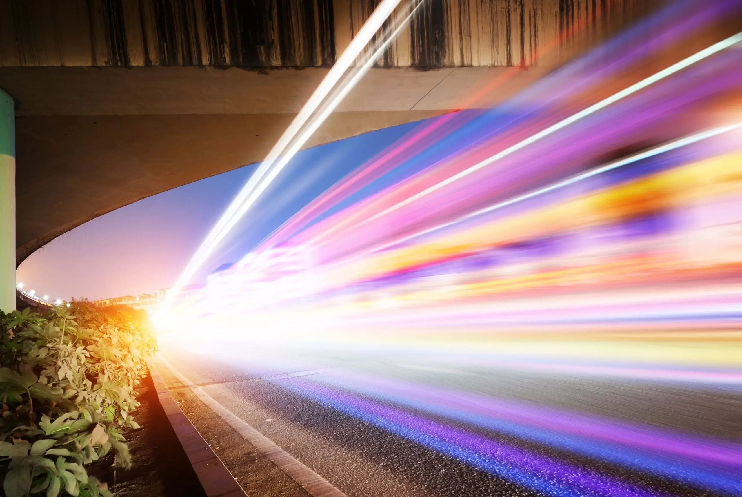 High-speed vehicles bright light trails on urban roads under the overpass at night